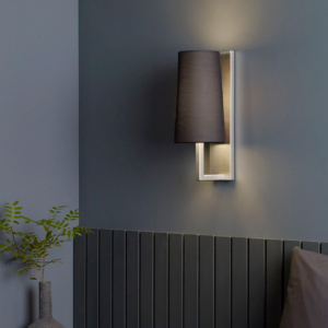 Riva lampa på en vägg ovan en säng.
