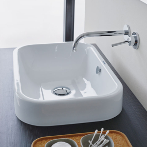 Happy D.2 tvättställ från Duravit för placering på bänk är monterad på en mörk bänkskiva med en vägghängd blandare.