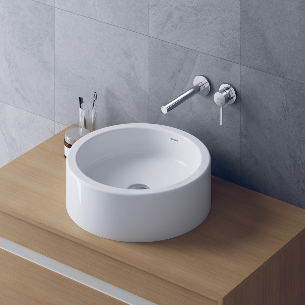 Starck 1 tvättställ för bänk från Duravit i en rund form på en bänkskiva i trä och en väggblandare.