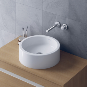 Starck 1 tvättställ för bänk från Duravit i en rund form på en bänkskiva i trä och en väggblandare.