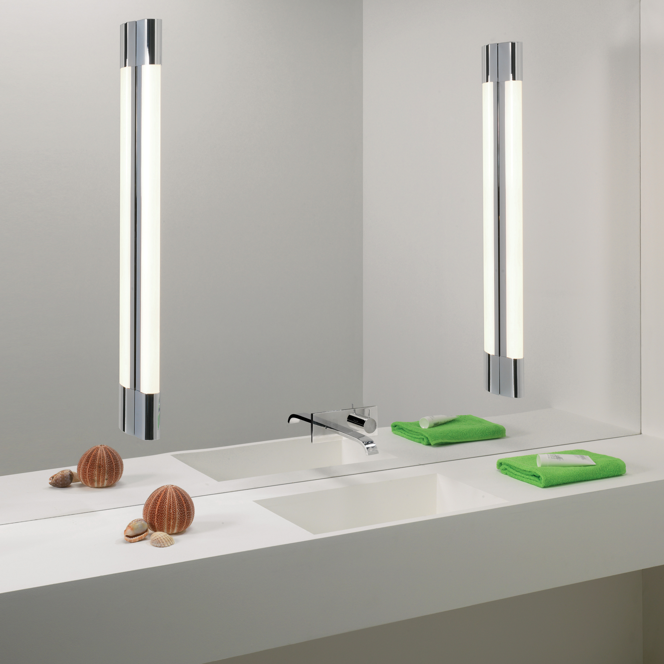 Palermo 900 LED vägglampa sittandes på vardera sida om en rektangulär spegel i ett badrum. Nedanför finns ett tvättställ och väggblandare.