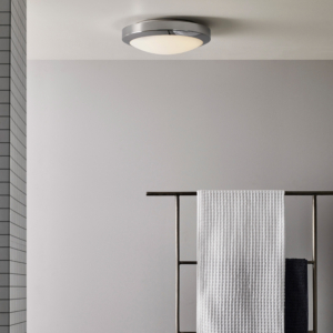 Dakota taklampa sitter i taket i ett badrum, på väggen hänger en hylla med handdukar.