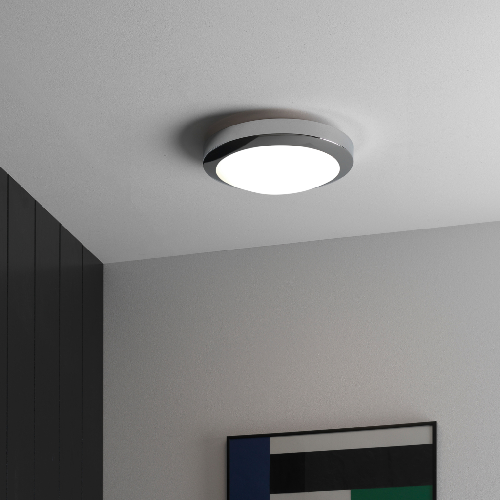 Dakota taklampa sitter i taket i ett badrum, på väggen hänger en hylla med handdukar.