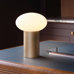 Zeppo Portable lampa med en rund glaskupa ståendes på en bänk.