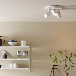 Ascoli Triple Round taklampa med 3 spotlights på en rund bas. under lampan på väggen finns en hylla med glas och ett bord med en skål med citroner.