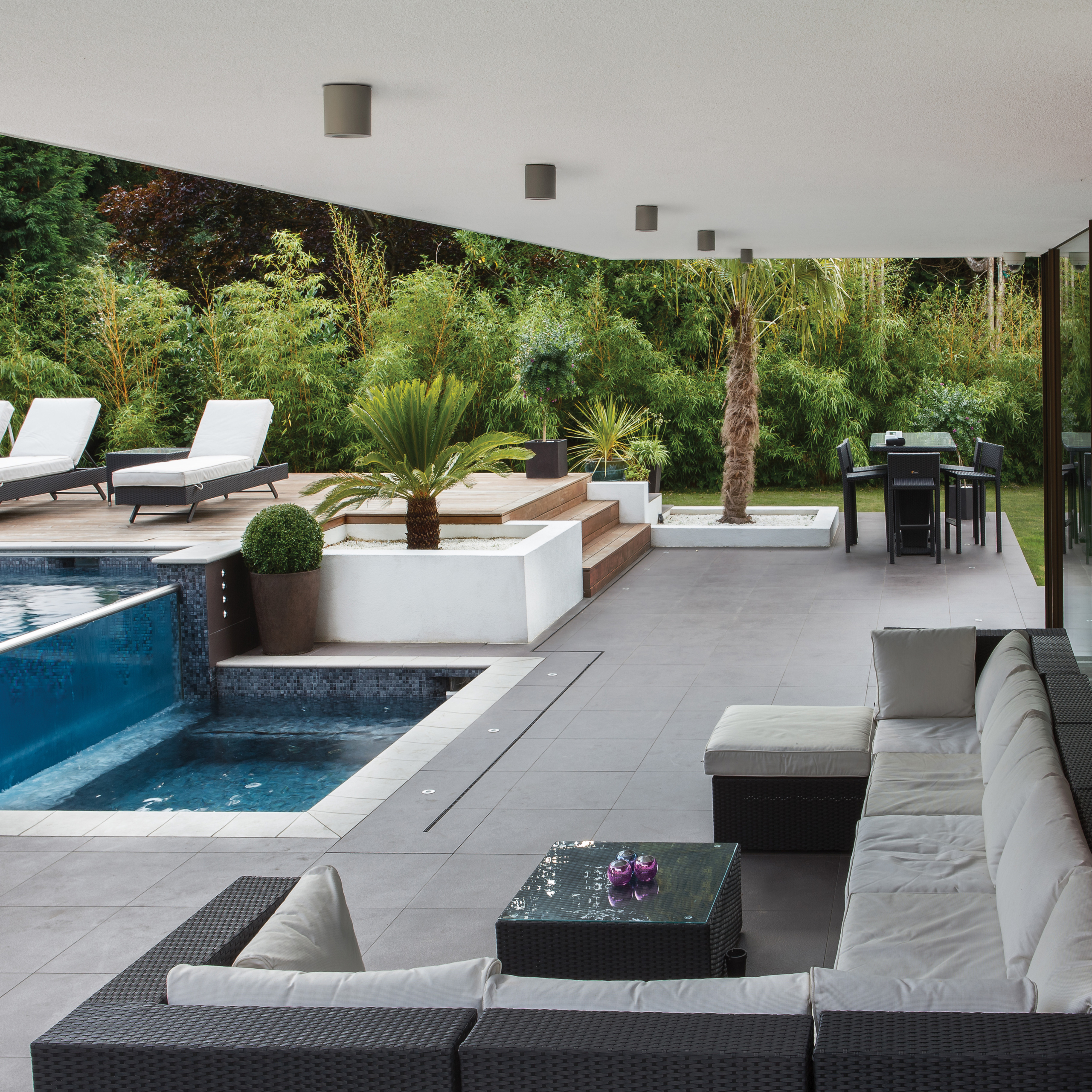 Kos Round downlight i betong som sitter i taket på en uteplats med stor loungesoffa och pool.