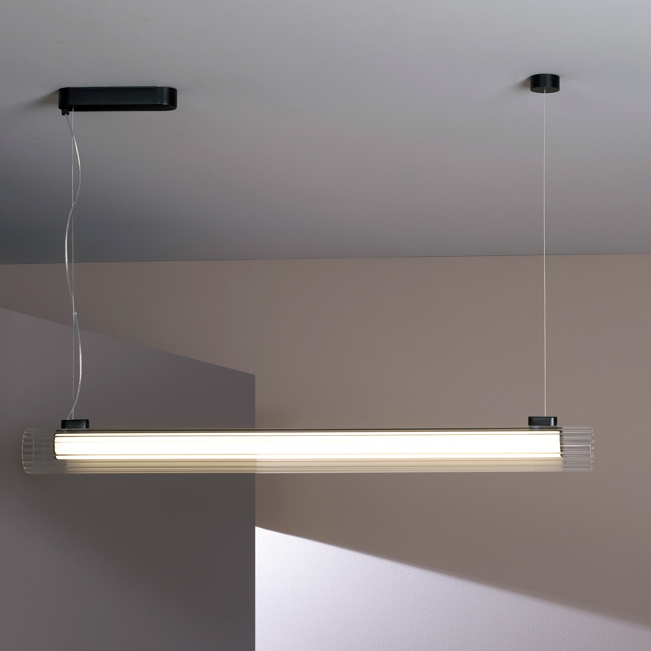 io Pendant 1000 taklampa, är en cylinderformad lampa som hänger från taket i två stållinor.