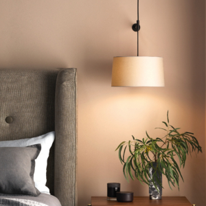 Tapered 320 Pendant lampskärm sittandes på en sänglampa ovanför ett sängbord med blomma och vid sidan om en säng.