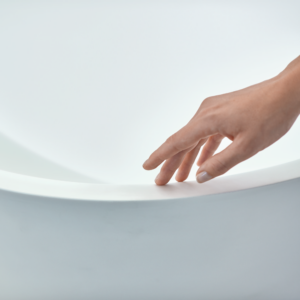 en hand som nuddar ett vit badkar.