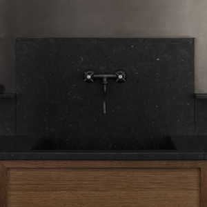 Kök med träskåp med svart stenbänkskiva. Väggköksblandare i en antik stilren design.