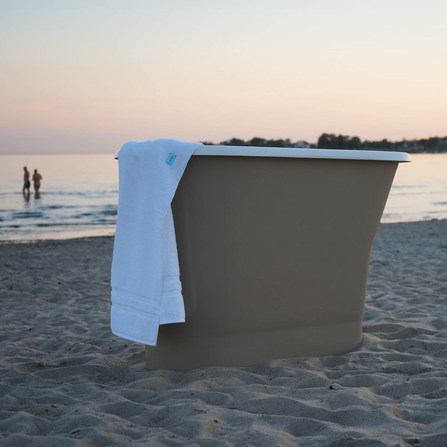 Monaco sittbadkar, vitt inuti och beige utsida, ståendes på en sandstrand. Från varumärket LH, Sanova.
