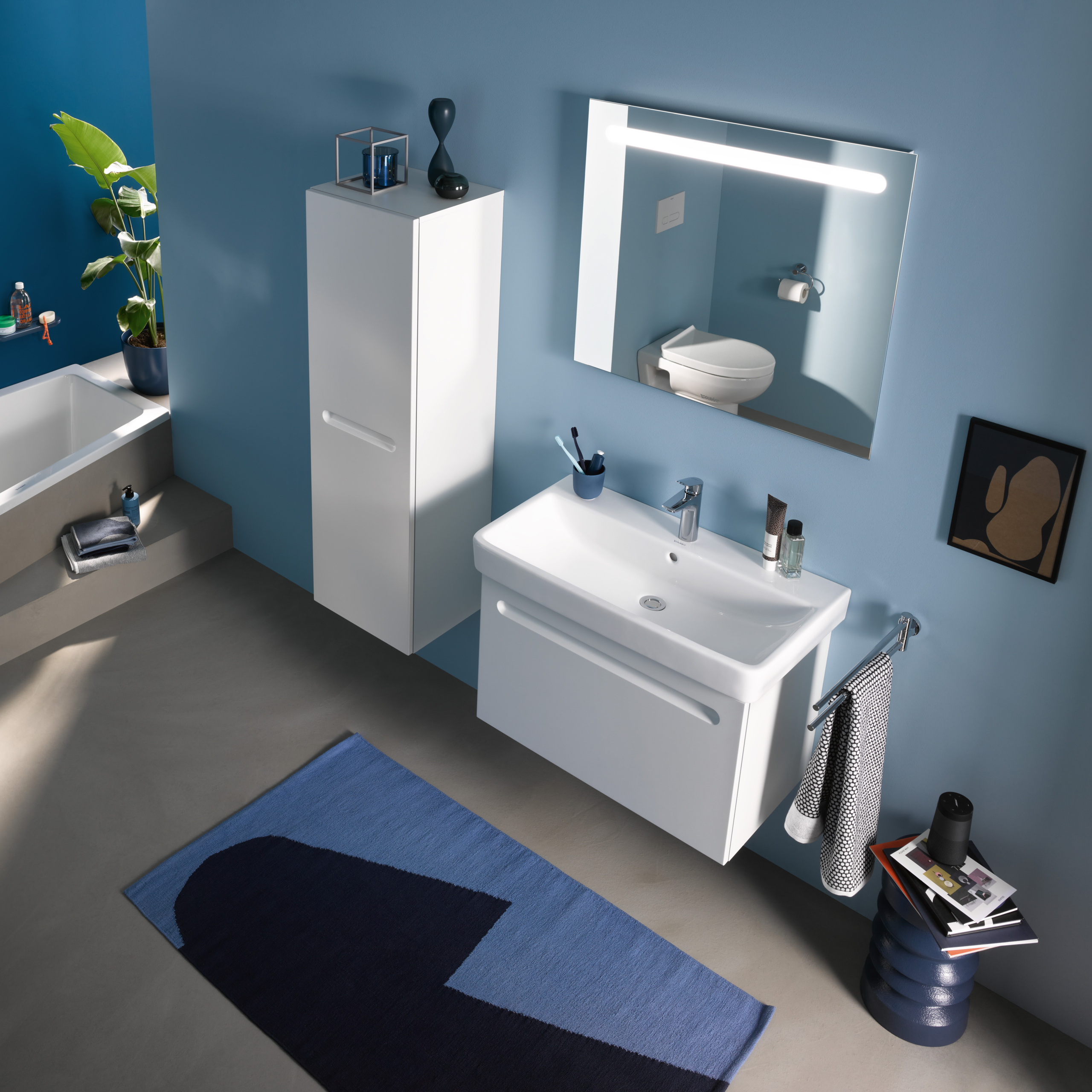 Kommod, högskåp och spegelskåp med belysning i ovankant från serien No.1 från Duravit i färgen vit. Sittandes på en blå vägg.