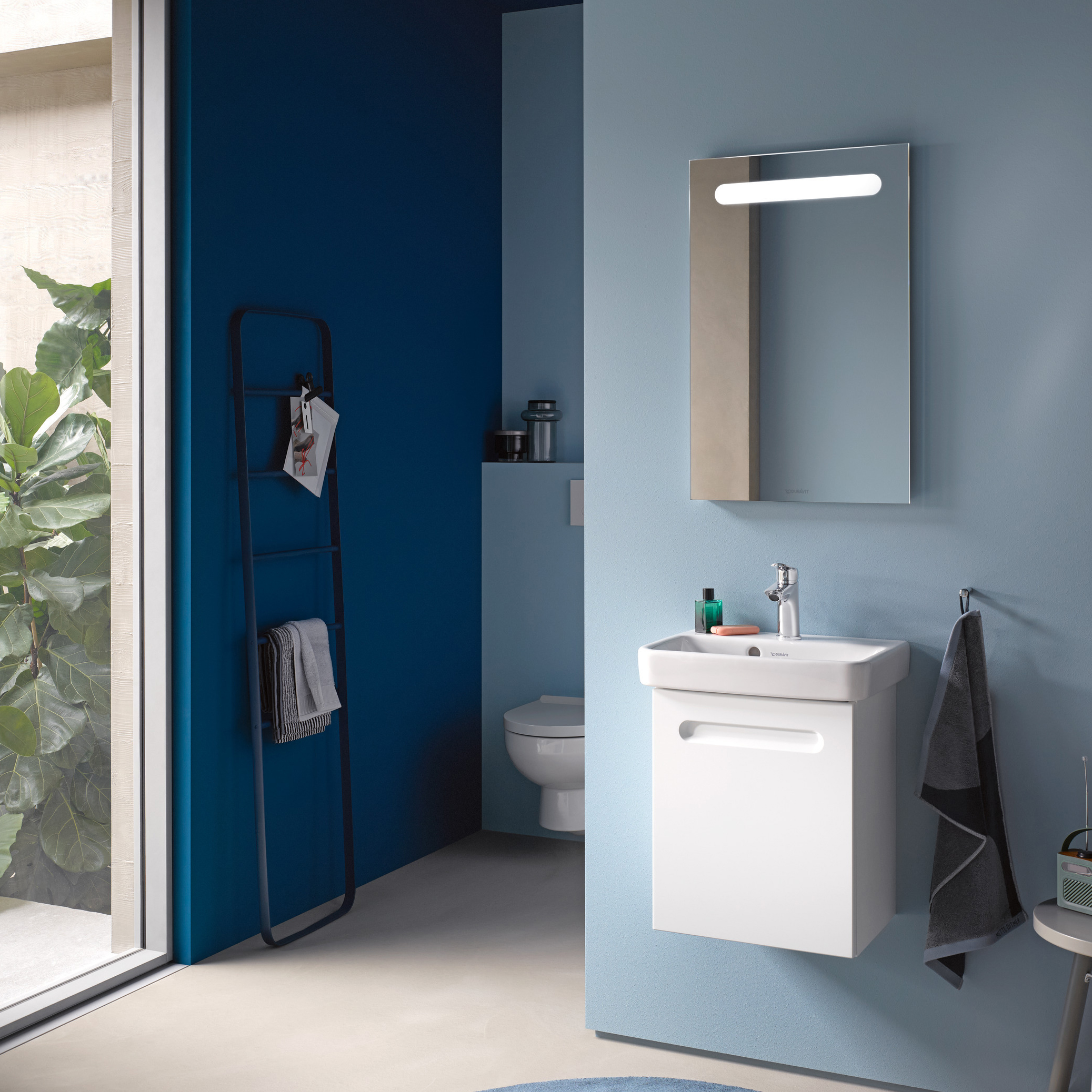 Kommod, högskåp och spegelskåp med belysning i ovankant från serien No.1 från Duravit i färgen vit. Sittandes på en blå vägg.