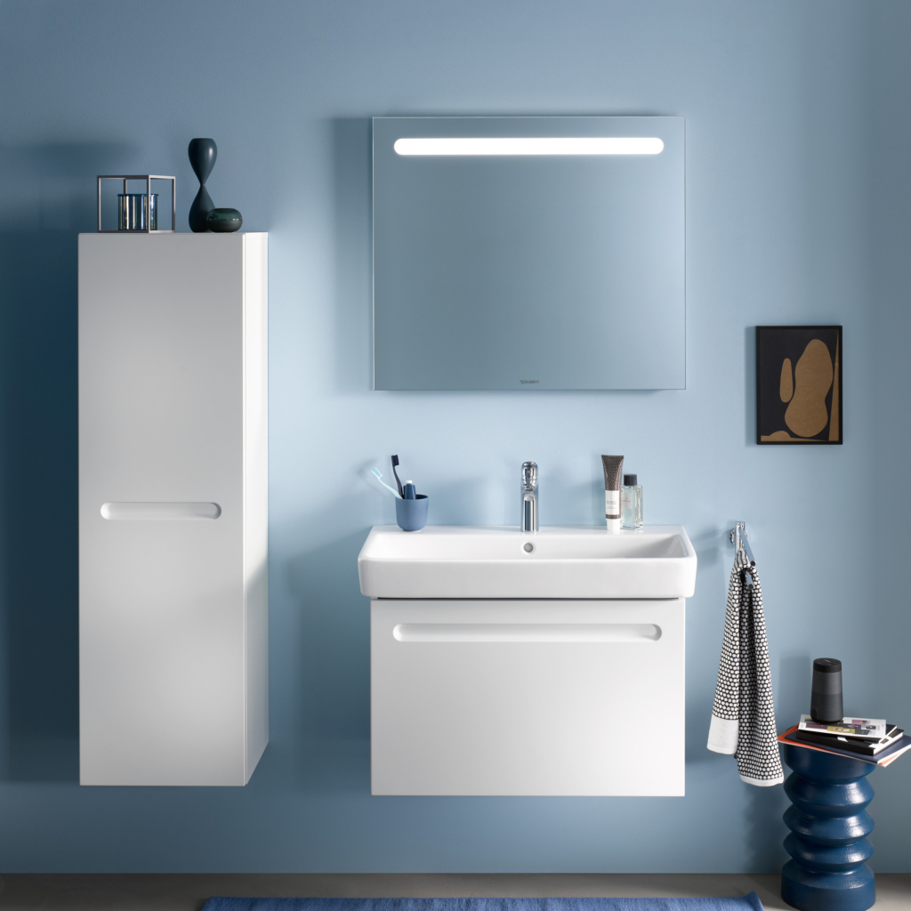 Kommod, högskåp och spegelskåp med belysning i ovankant från serien No.1 från Duravit i färgen vit. Sittandes på en blå vägg.