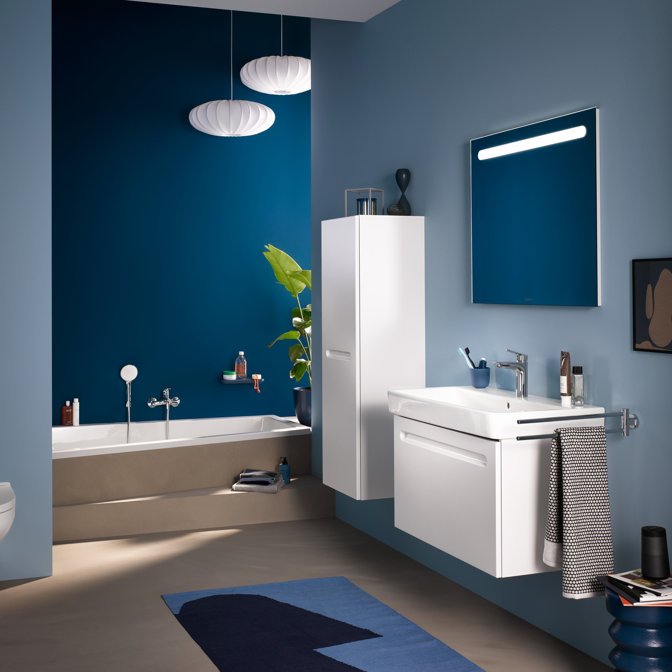 Kommod, högskåp och spegelskåp med belysning i ovankant från serien No.1 från Duravit i färgen vit. Sittandes på en blå vägg.