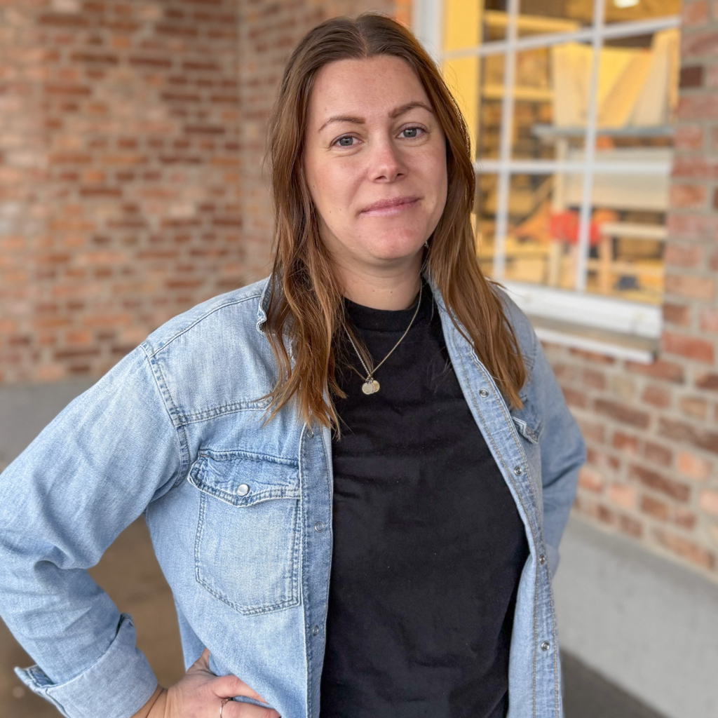 Tjej med långt brunt hår, klädd i svart t-shirt och jeansskjorta.