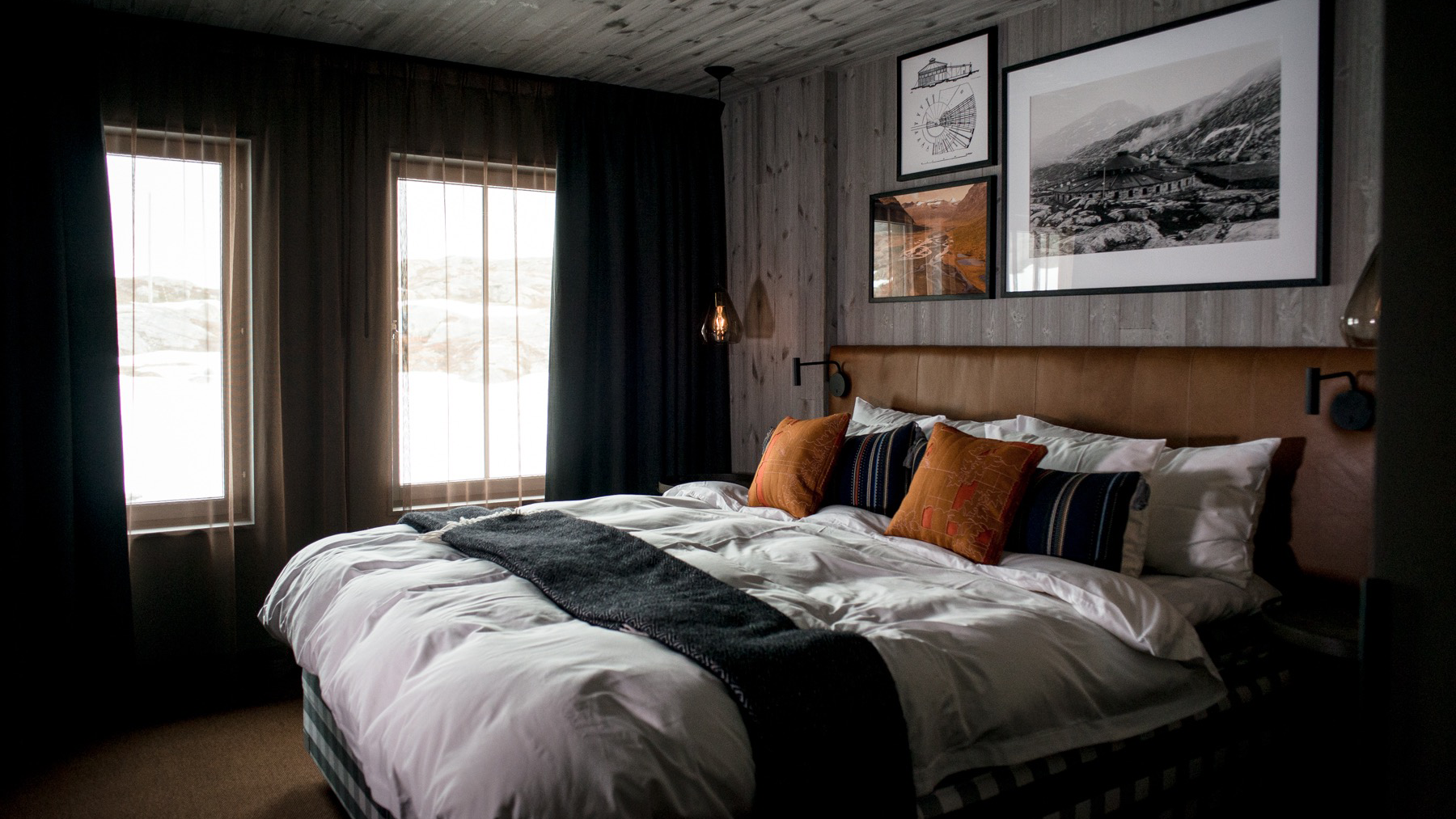 Sovrum med träväggar, stor och härlig säng med många kuddar.
