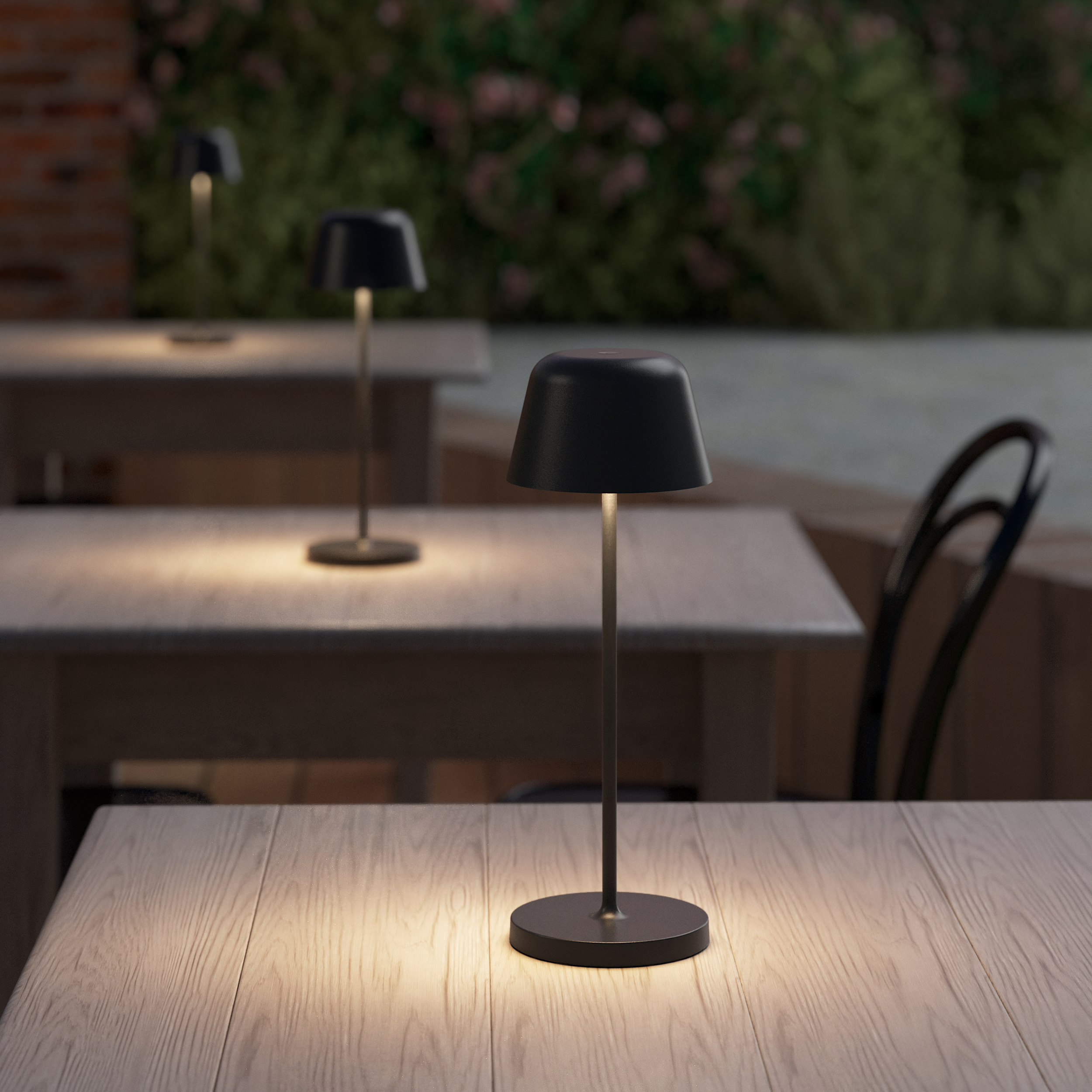 Nomad bordslampa på ett träbord.
