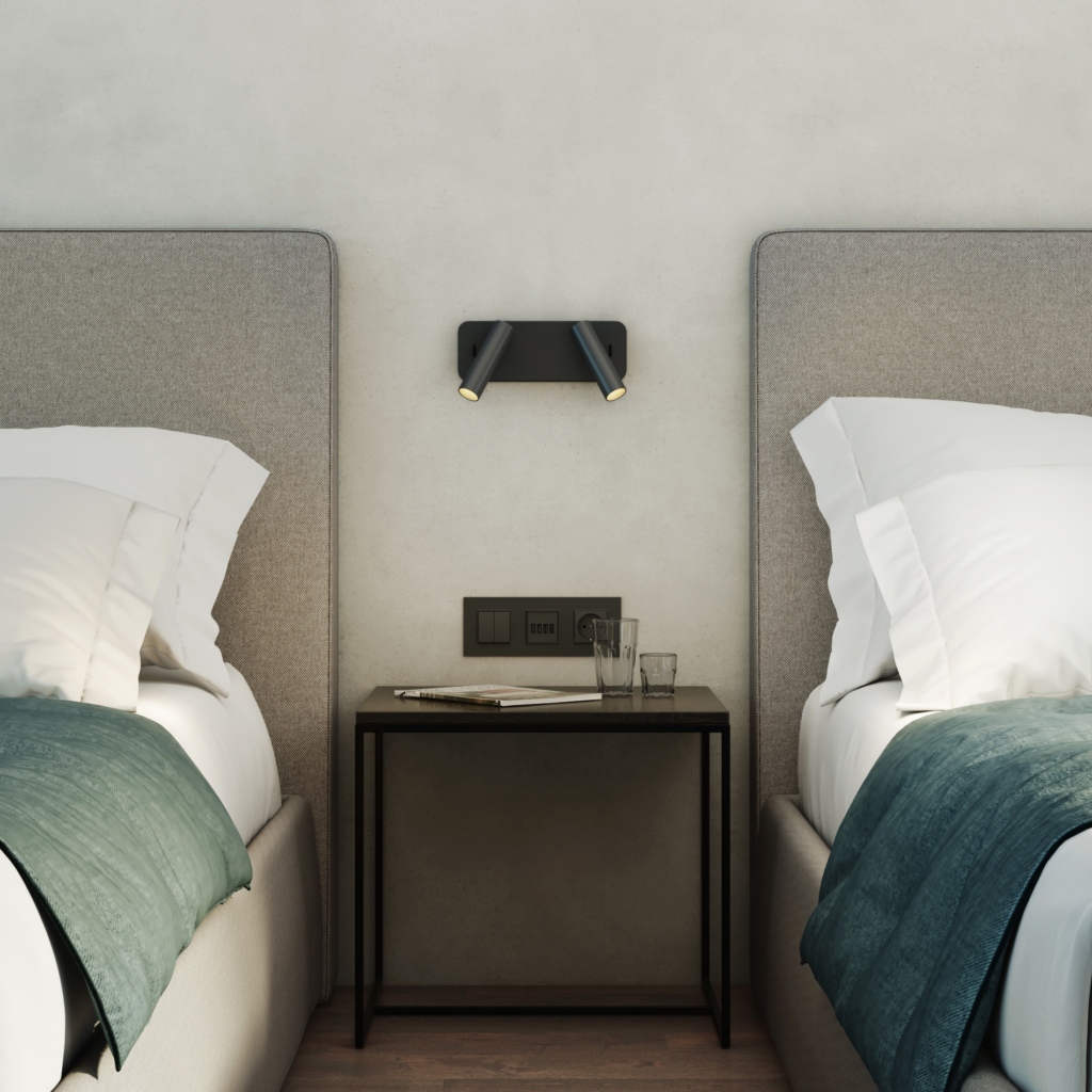Enna Twin sänglampa, läslampa på en vägg mellan två sängar, ovanför ett sängbord.