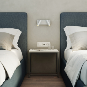 Enna Twin sänglampa, läslampa på en vägg mellan två sängar, ovanför ett sängbord.