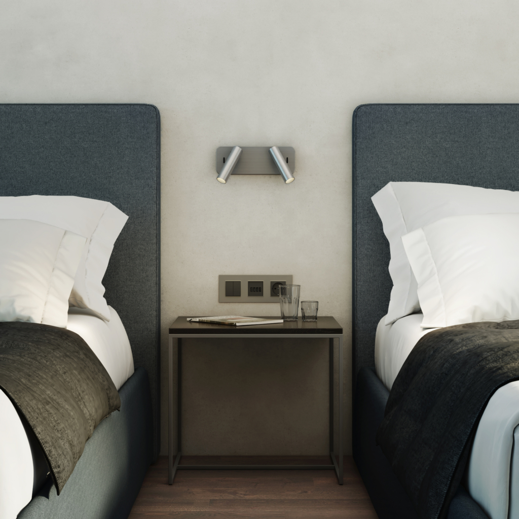 Enna Twin sänglampa, läslampa på en vägg mellan två sängar, ovanför ett sängbord.