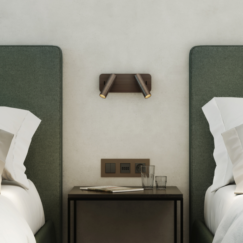 Enna Twin sänglampa, läslampa på en vägg mellan två sängar, ovanför ett sängbord.