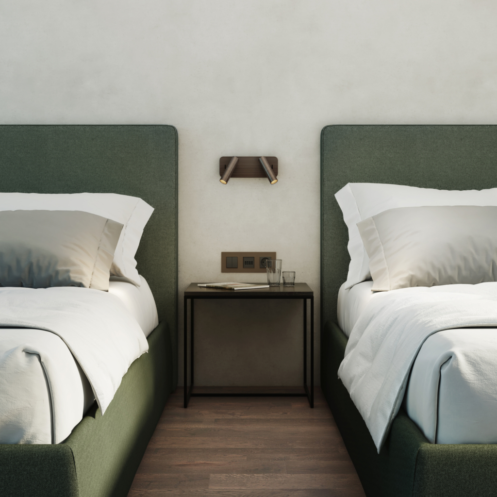 Enna Twin sänglampa, läslampa på en vägg mellan två sängar, ovanför ett sängbord.