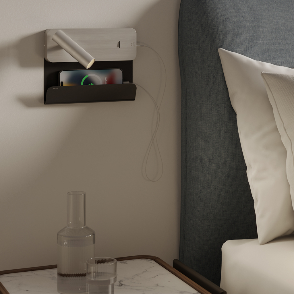 Enna Surface USB läslampa för vägg med hylla för mobil bredvid en säng.