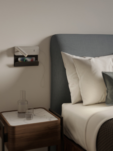 Enna Surface USB läslampa för vägg med hylla för mobil bredvid en säng.