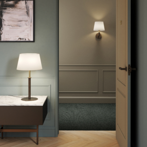 Club Table bordslampa med skärm på ett bord bredvid en fåtölj.Club wall vägglampa sitter på väggen bakom.