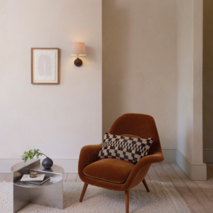 Club Wall vägglampa med lampskärm som sitter på en vägg i ett rum med fåtölj, litet runt bord och en tavla bredvid lampan.