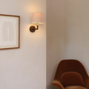 Club Wall vägglampa med lampskärm som sitter på en vägg i ett rum med fåtölj och en tavla bredvid lampan.