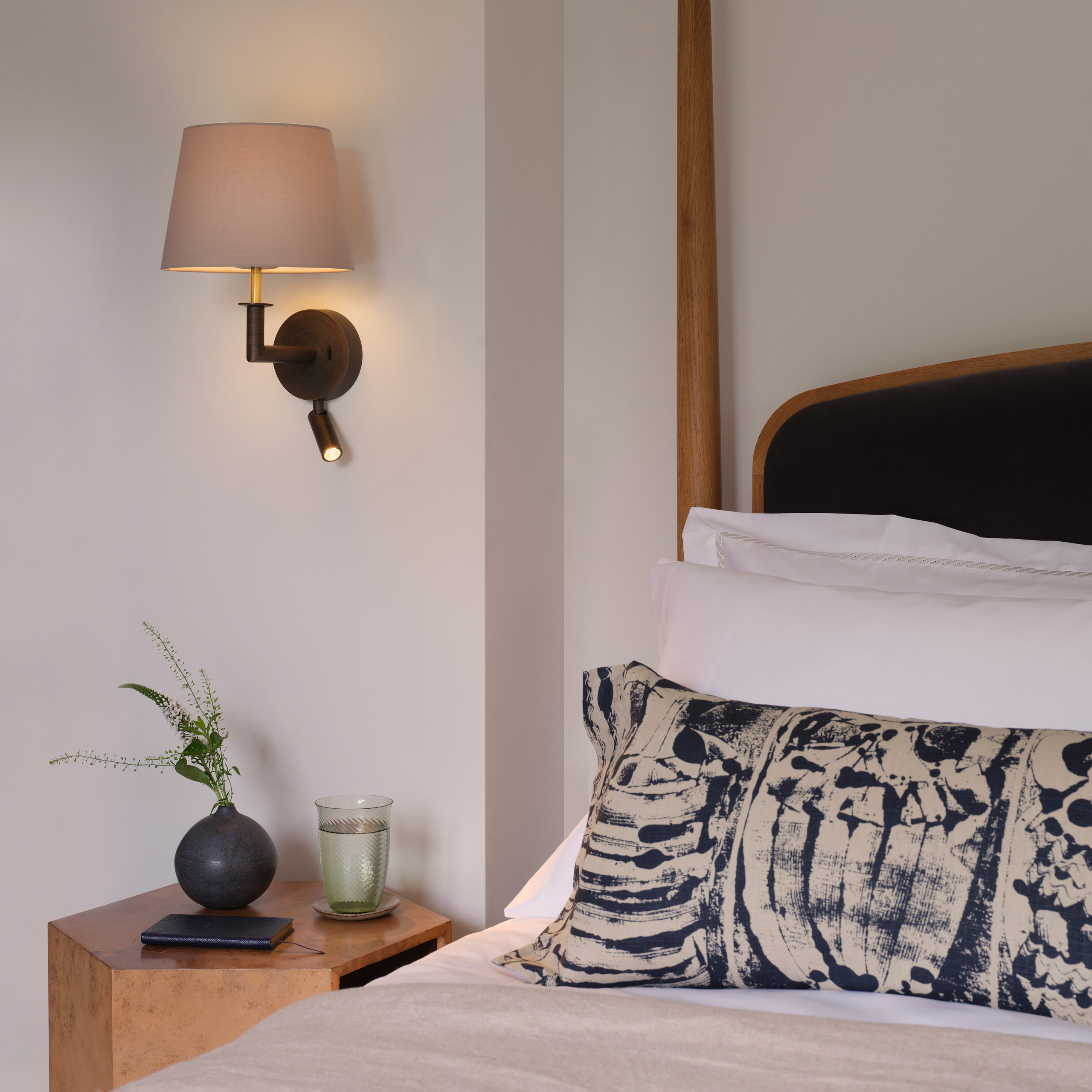 Club Reader, läslampa med skärm på en vägg vid en säng.