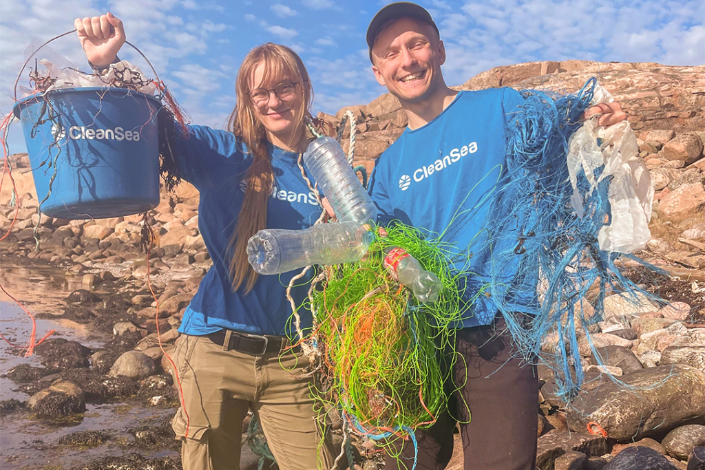 En tjej och en kille, klädda i blå t-shirt med märket CleanSea visar upp rep, flaskor och plast